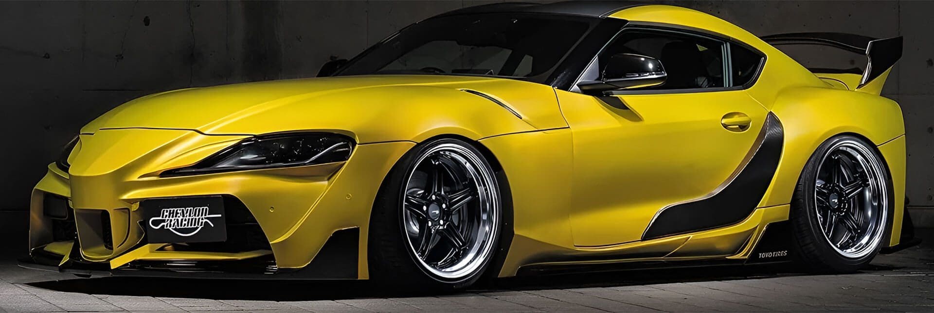 A yellow sports car with black wheels parked in a parking lot.