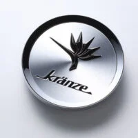 A silver button with the word kranze on it.