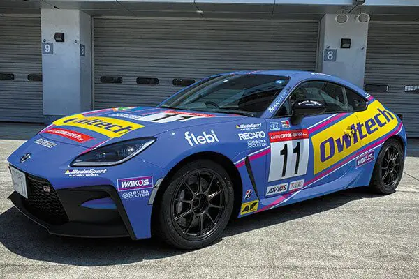 A toyota 86 race car parked in front of a garage.