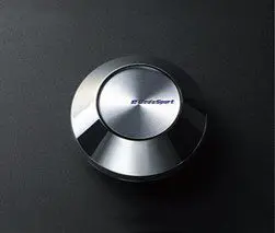 A silver button on a black surface.