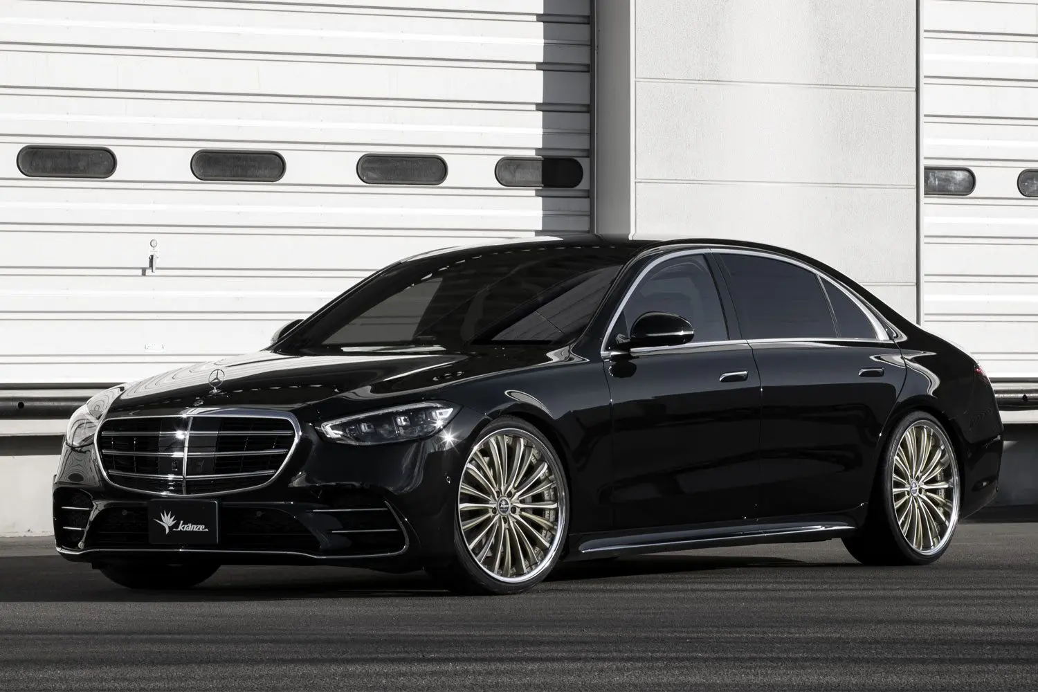 The black mercedes s class is parked in front of a garage.