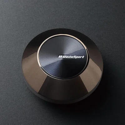 A black button on a black surface.