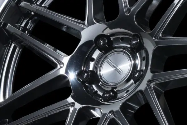 A close up of a chrome wheel on a black background.
